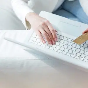 Hands of female sitting at the laptop with a credit card